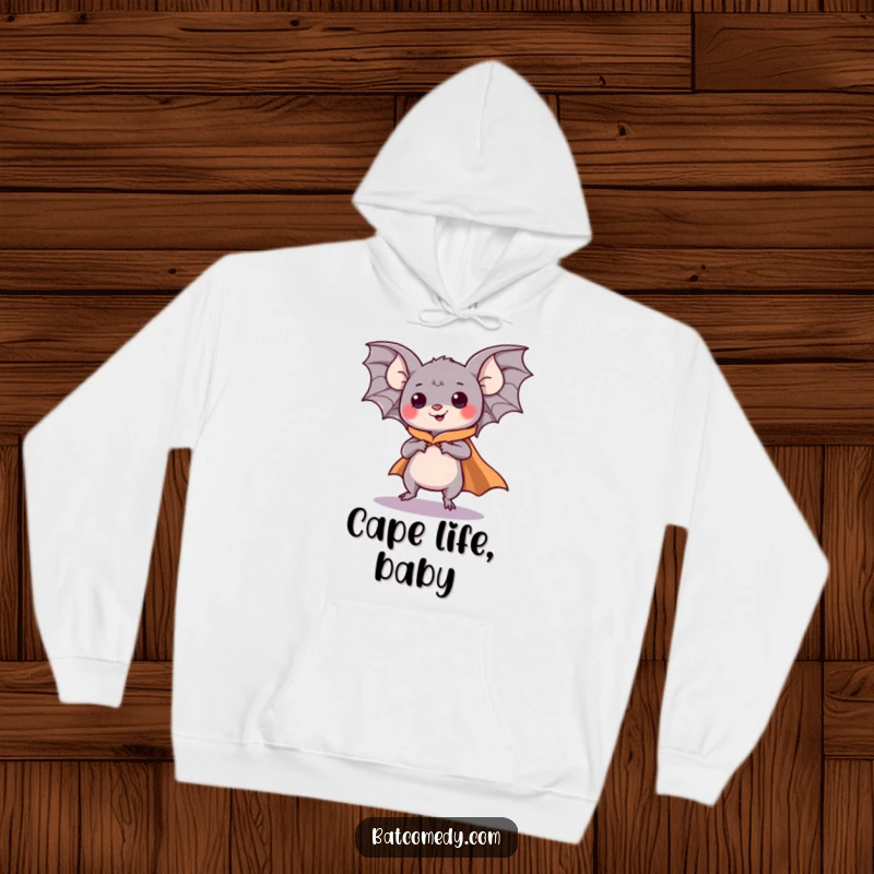 Funny kawaii bat wearing a superhero cape, comically pretending to fly with enthusiasm on a cozy hoodie.
