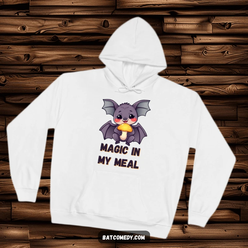 Funny hoodie featuring a smiling bat holding a glowing mushroom, radiating a sense of wonder and cozy magic.