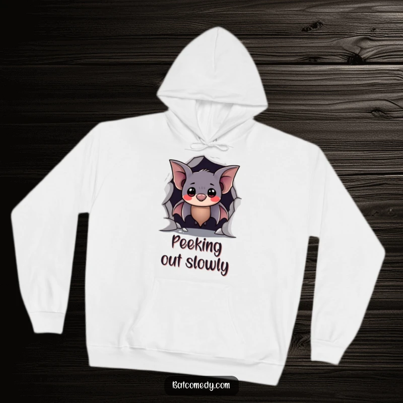 Funny hoodie of a shy bat peeking from a cave with a hesitant, sweet smile, offering warmth and bashful humor.